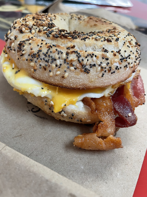 A bagel sandwich with eggs and bacon